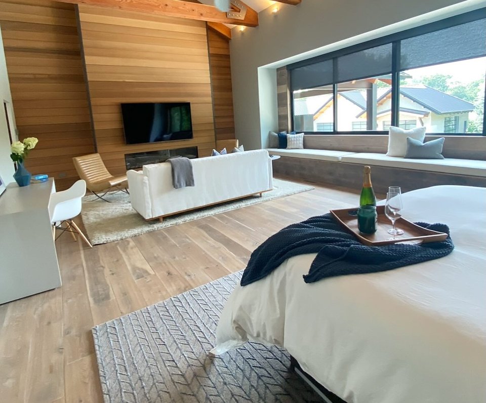 A staged primary bedroom with layered, neutral bedding
