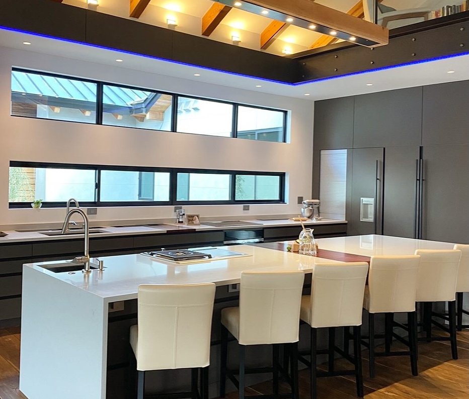 A vaulted-ceiling kitchen with a long white island and cream stools