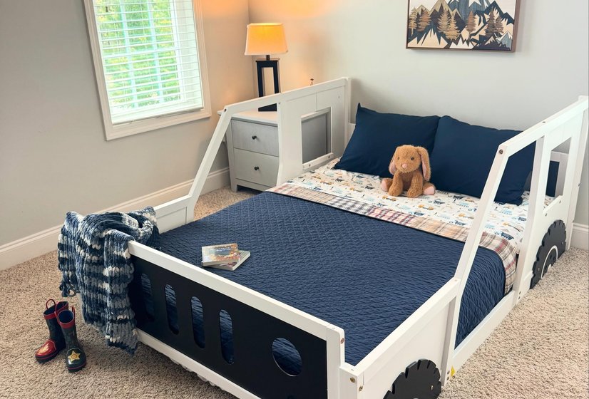 A child's room with a navy truck bed and cozy bedding