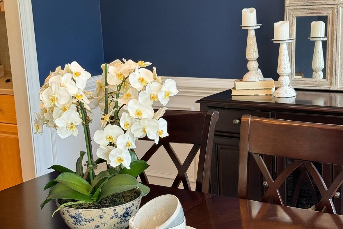 A styled dining table with white orchids in a blue-and-white bowl