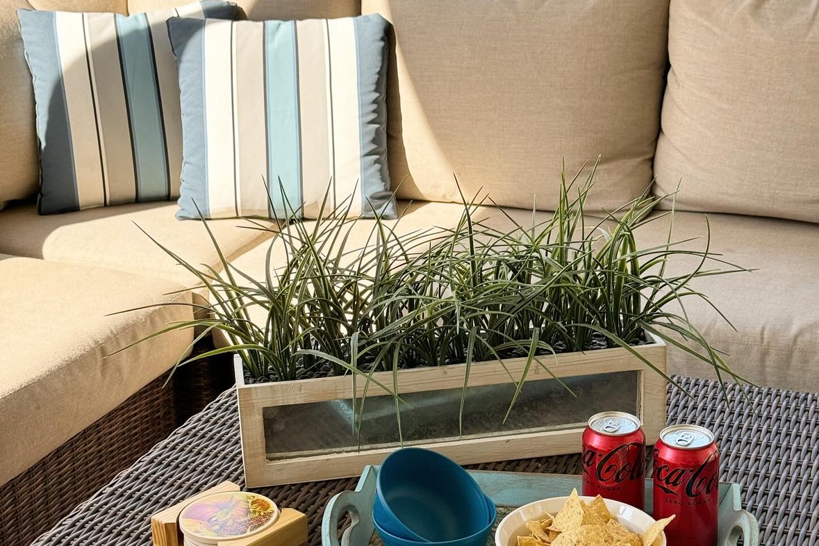 A styled sectional with a snack tray and a potted grass centerpiece