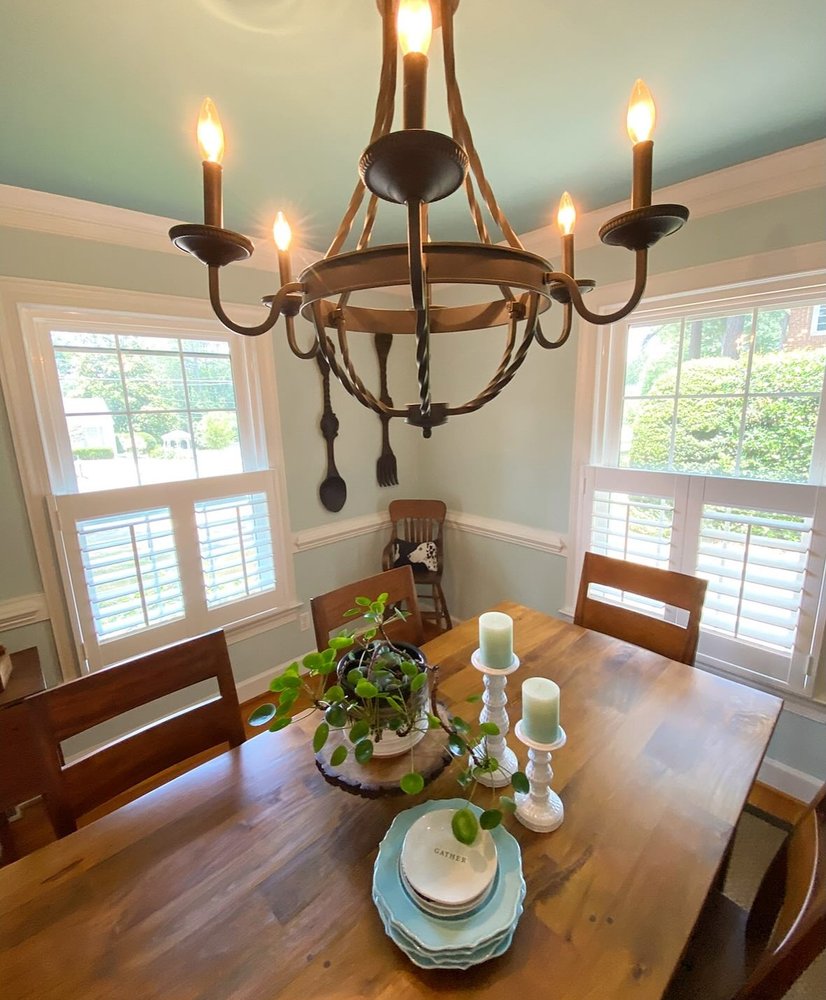 A dining table styled with a plant, candles and blue plates under a rustic chandelier